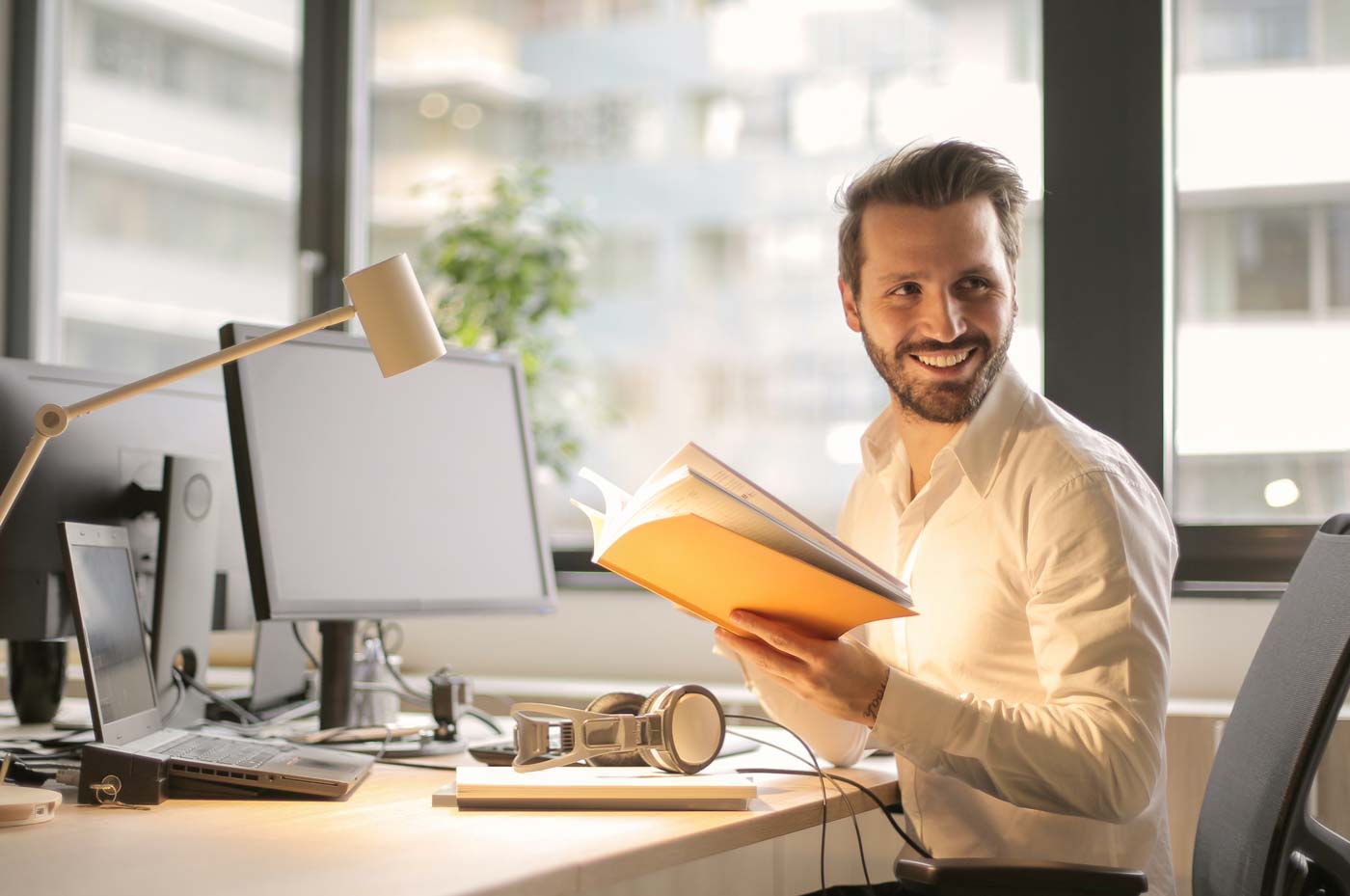 A man at his desk holding a book